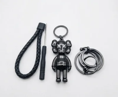 ميدالية مفاتيح سيارة فاخرة بتصميم شخصية (KAWS) الشهيرة باللون الأسود اللامع، مصممة بعناية من خامات معدنية وجلدية عالية الجودة لتضيف لمسة راقية وعصرية لمفاتيح سيارتك.