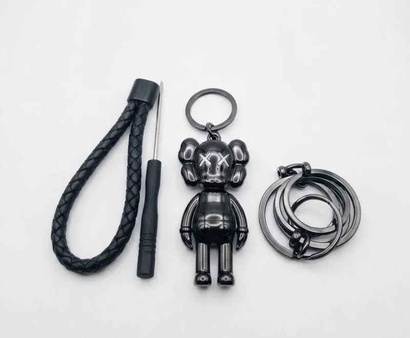 ميدالية مفاتيح سيارة فاخرة بتصميم شخصية (KAWS) الشهيرة باللون الأسود اللامع، مصممة بعناية من خامات معدنية وجلدية عالية الجودة لتضيف لمسة راقية وعصرية لمفاتيح سيارتك.